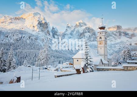 L'église distinctive de Colfosco (Kolfuschg) près de Corvara avec le groupe Sella Dolomites montagnes sous une couche de neige fraîche à Alta Badia, Italie. Banque D'Images