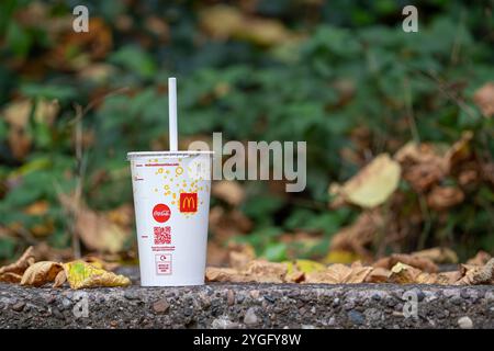 Gobelet en papier McDonalds désutilisé avec de la paille jetée sur un mur extérieur en pierre. Banque D'Images