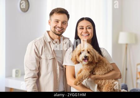 Portrait de couple de famille heureux tenant chien ensemble à la maison Banque D'Images