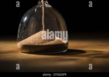 Grains de sable dorés scintillants coulant dans un sablier, vue macro. Matériau, texture et concepts abstraits. Banque D'Images