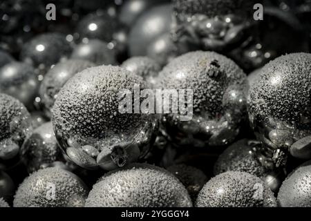 Décoration festive, neige tombant sur des boules argentées de Noël avec des lumières dorées discrètes floues en arrière-plan, gros plan. Banque D'Images
