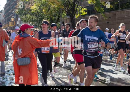 À la barre des 10 miles du marathon de New York 2024, les bénévoles gardent les coureurs hydratés avec des tasses d'eau. Sur Bedford Avenue à Williamsburg, Brooklyn, N. Banque D'Images