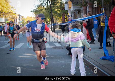 Lors du marathon de NY 2024, une adolescente gifle les coureurs qui passent par faire de la course une expérience commune. À la marque de 10 miles à Williamsburg, Bklyn. Banque D'Images