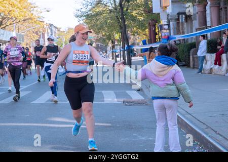 Lors du marathon de NY 2024, une adolescente gifle les coureurs qui passent par faire de la course une expérience commune. À la marque de 10 miles à Williamsburg, Bklyn. Banque D'Images