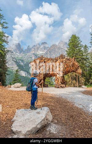 L'enfant regarde avec stupéfaction cette gigantesque sculpture en bois d'un ours brun. Europe, Italie, Trentino Tyrol du Sud, non vallée, Pradel, Molveno, Tren Banque D'Images