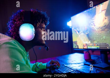 Photo de mignon jeune gars stressé perdre le jeu jouer joueur ordinateur violet bleu néon lumière à l'intérieur tard dans la nuit Banque D'Images