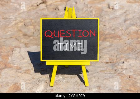 Symbole heure des questions. Mots conceptuels heure des questions sur le beau tableau noir de craie jaune. Beau fond de plage en pierre. Heure des affaires et des questions c Banque D'Images