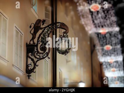 Couronne décorative suspendue à un support métallique sur un bâtiment. La couronne est entourée d'une tête de lion, qui fait également partie de la décoration. La scène Banque D'Images