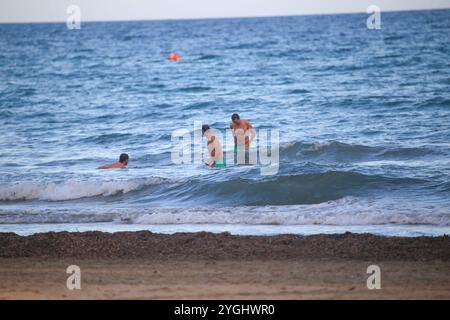 Alicante, Espagne, 07 novembre 2024 : trois hommes se baignant à Playa del Postiguet pendant la vie quotidienne à Alicante, le 07 novembre 2024, à Alicante, Espagne. Crédit : Alberto Brevers / Alamy Live News. Banque D'Images