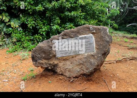 Un grand rocher avec une plaque commémorative apposée dessus, au sol, entouré de végétation, dans le jardin botanique du cratère de Koko, Honolulu, Oahu, Hawaï Banque D'Images