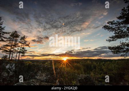 Paysage photographié dans une forêt de pins. Vue d'un rocher sur les arbres. Coucher de soleil romantique à l'horizon dans la soirée à Amal, Suède Banque D'Images