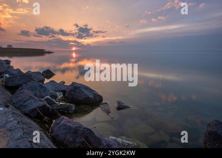 Paysage aquatique, pris de la rive d'un lac calme. Vue sur l'eau réfléchissante à l'horizon au coucher du soleil. Port de Siófok, Lac Balaton, Hongrie Banque D'Images