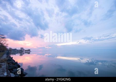 Paysage aquatique, pris de la rive d'un lac calme. Vue sur l'eau réfléchissante à l'horizon au coucher du soleil. Port de Siófok, Lac Balaton, Hongrie Banque D'Images