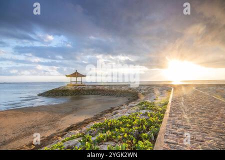 Lever de soleil fantastique sur la plage avec de petits temples et construit comme brise-lames. Vue sur la mer jusqu'à l'horizon. Sanur, Bali, Indonésie Banque D'Images