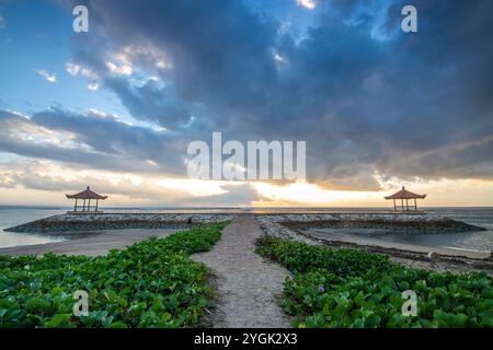 Lever de soleil fantastique sur la plage avec de petits temples et construit comme brise-lames. Vue sur la mer jusqu'à l'horizon. Sanur, Bali, Indonésie Banque D'Images