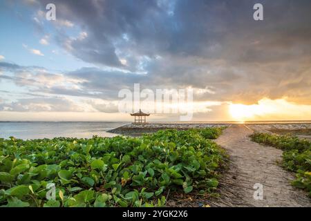 Lever de soleil fantastique sur la plage avec de petits temples et construit comme brise-lames. Vue sur la mer jusqu'à l'horizon. Sanur, Bali, Indonésie Banque D'Images