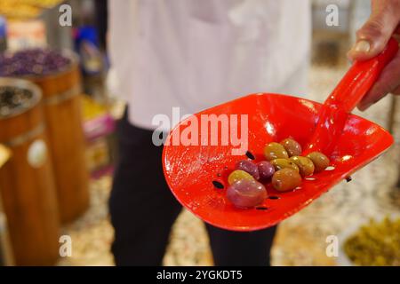 Une variété d'olives colorées servies de façon experte dans un plat rouge vif Scoop aujourd'hui Banque D'Images