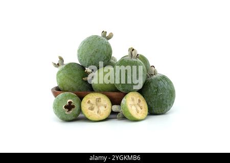 Collection de feijoas fraîches exposées dans un bol en bois sur fond blanc. L'image capture la couleur vibrante et la texture de ces tropicaux Banque D'Images