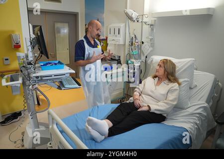 Rob McDonnell, animateur principal de la pratique clinique, discutant avec la patiente Katie Tinkler avant qu'elle ne reçoive un traitement révolutionnaire pour le lupus à l'University College London Hospital de Londres. Trois patients au Royaume-Uni ont reçu un traitement « révolutionnaire » pour le lupus sur le NHS, qui, selon les experts, pourrait éradiquer le besoin de médicaments à vie. Jusqu'à présent, la thérapie par les cellules T CAR agit en modifiant génétiquement le propre système immunitaire du corps pour reconnaître et attaquer les cellules problématiques, offrant aux gens un remède possible. Date de la photo : mercredi 6 novembre 2024. Banque D'Images