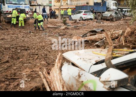 Alfafar, Valence, Espagne - 7 novembre 2024. Travailleurs spécialisés de EMT Madrid, Empresa Municipal de Transportes de Madrid, nettoyage d'un parc à Alfafar, Communauté valencienne. Ils utilisent des camions et des cordes pour enlever les voitures coincées entre la terre et la boue. Ils les amènent à un parking vide fermé où ils les empilent les uns sur les autres. Banque D'Images