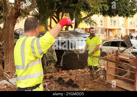 Alfafar, Valence, Espagne - 7 novembre 2024. Travailleurs spécialisés de EMT Madrid, Empresa Municipal de Transportes de Madrid, nettoyage d'un parc à Alfafar, Communauté valencienne. Ils utilisent des camions et des cordes pour enlever les voitures coincées entre la terre et la boue. Ils les amènent à un parking vide fermé où ils les empilent les uns sur les autres. Banque D'Images