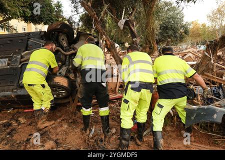 Alfafar, Valence, Espagne - 7 novembre 2024. Travailleurs spécialisés de EMT Madrid, Empresa Municipal de Transportes de Madrid, nettoyage d'un parc à Alfafar, Communauté valencienne. Ils utilisent des camions et des cordes pour enlever les voitures coincées entre la terre et la boue. Ils les amènent à un parking vide fermé où ils les empilent les uns sur les autres. Banque D'Images