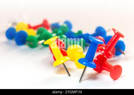 Une collection de punaises multicolores dispersées sur une surface blanche, mettant en valeur des teintes vives de rouge, bleu, jaune et vert Banque D'Images