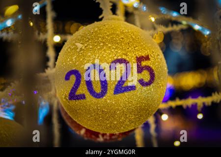 Élégant sapin de Noël décoré de ballons dorés. Un jouet de Noël jaune avec le numéro 2025. Le début de la nouvelle année. Banque D'Images