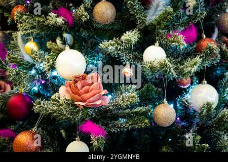 Un élégant arbre de Noël décoré de boules rouges et dorées . Carte de Noël. Décoration de rue du nouvel an. Rose sur la branche de l'arbre de Noël Banque D'Images