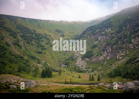 Le lac Maly Staw dans les montagnes Karkonosze émerge à travers la brume, créant un paysage de montagne serein et brumeux. Banque D'Images