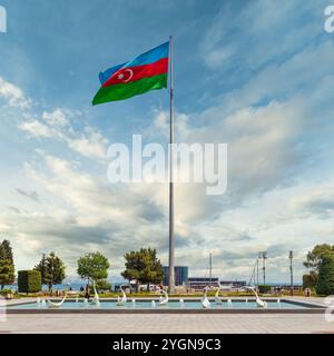 Bakou, Azerbaïdjan - 10 mai 2024 : la fontaine des cygnes ornée d'élégantes statues de cygne, tandis que le drapeau national azerbaïdjanais oscille fièrement contre un beau ciel clair, créant une vue pittoresque Banque D'Images