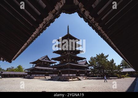 Un homme marche devant la pagode de cinq étages du temple bouddhiste Horyuji à Nara. Le temple et la pagode ont plus de 1400 ans Banque D'Images