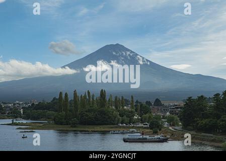 Un bateau et un homme sur un bateau de pêche sur un lac en face du volcan Fuji de 3776 mètres de haut, la plus haute montagne du Japon et le point de repère du pays. C Banque D'Images