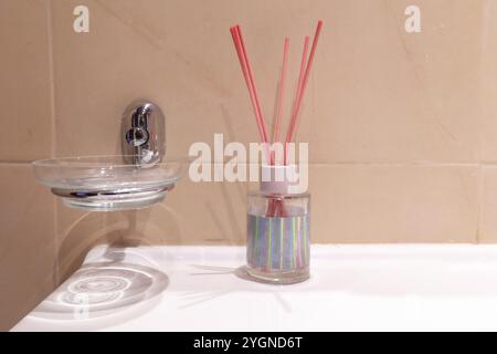 Pot en verre avec bâtons aromatiques en bois et porte-savon dans la salle de bain Banque D'Images