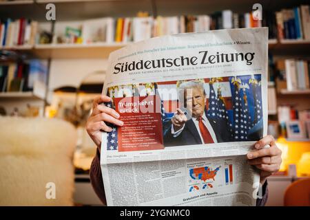 Paris, France - 7 novembre 2024 : femme lisant le journal allemand Suddeutsche Zeitung avec un titre sur le retour au pouvoir de Donald Trump lors des récentes élections américaines Banque D'Images