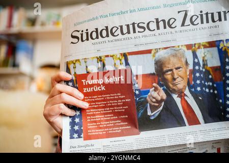 Paris, France - 7 novembre 2024 : gros plan d'une femme lisant Suddeutsche Zeitung dans un salon confortable, avec un titre sur la victoire électorale de Donald Trump et son retour à la politique américaine Banque D'Images