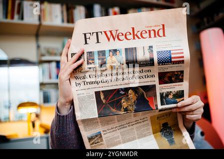 Paris, France - 7 novembre 2024 : femme lisant FT Weekend dans un salon confortable, avec un titre de première page sur la création d'emplois aux États-Unis et la réponse de Trump avant les élections. Banque D'Images