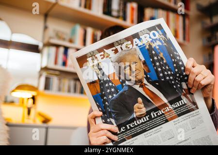 Paris, France - 7 novembre 2024 : personne lisant le journal français le Figaro dans un salon confortable, avec un titre de première page sur le retour impactant de Donald Trump à la politique américaine Banque D'Images