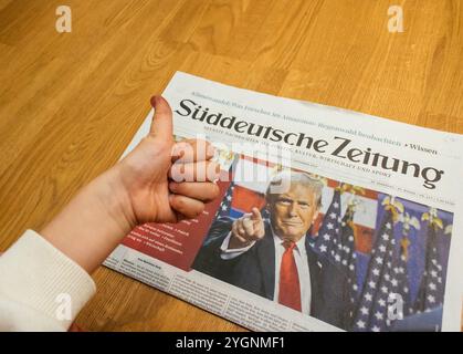 Paris, France - 7 novembre 2024 : curieux garçon en bas âge donnant un pouce vers le haut à la première page de Suddeutsche Zeitung avec un titre sur Donald Trump retour à la politique américaine. Suddeutsche Zeitung traduit au journal sud-allemand Banque D'Images