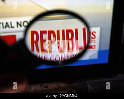 Paris, France - 6 novembre 2024 : main masculine tenant une loupe à l'écran de télévision montrant DES RÉPUBLICAINS pendant la couverture de la nuit des élections américaines, soulignant l'accent intense mis sur les résultats politiques. Banque D'Images