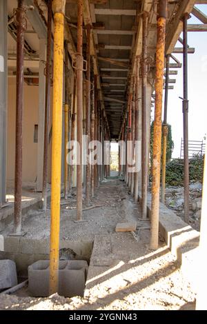 Un couloir de chantier soutenu par des échafaudages métalliques, montrant le béton brut et les surfaces non finies. Banque D'Images