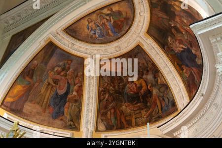 Des fresques vives représentant des scènes de la Bible décorent le plafond incurvé d'une église, mettant en valeur l'art religieux et l'histoire Banque D'Images