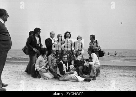 Die rumänische Pop-Sängerin Angela Similea umringt von Pressefotografen am Strand von Sopot, WO sie beim Intervision Song Contest 1977 (Sopot 77) zusammen mit Olimpia Panciu und Marius Teicu [Ţeicu] auf den 9. Platz und mit ihrem Solo-Auftritt auf den 18. Platz kam. Unten, vorne sitzt der DDR-Fotograf Tassilo Leher ; Am rechten Bildrand wird eine Strandgängerin aus dem Bild gewunken, Polen 1977. Banque D'Images