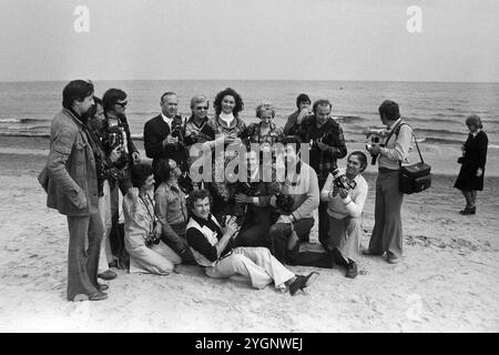 Die rumänische Pop-Sängerin Angela Similea umringt von Pressefotografen am Strand von Sopot, WO sie beim Intervision Song Contest 1977 (Sopot 77) zusammen mit Olimpia Panciu und Marius Teicu [Ţeicu] auf den 9. Platz und mit ihrem Solo-Auftritt auf den 18. Platz kam. Unten, vorne sitzt der DDR-Fotograf Tassilo Leher ; Am rechten Bildrand wird eine Strandgängerin aus dem Bild gewunken, Polen 1977. Banque D'Images