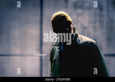 Suspect criminel et étranger homme dans la rue sombre. Harceleur se cachant dans l'ombre. Silhouette et visage caché d'un voleur. Gangster méchant. Banque D'Images