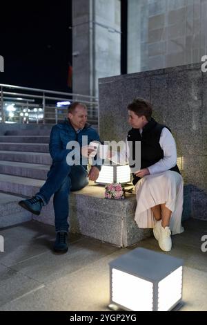 Un couple marié profite d'une soirée en ville, partageant un café et un rire Banque D'Images