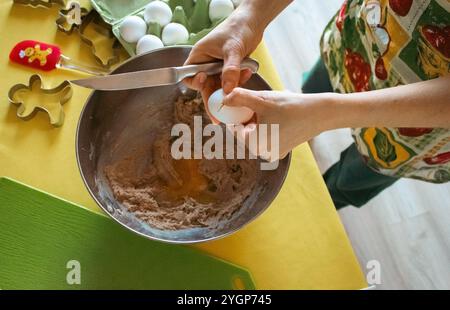 Femme dans le tablier faisant la pâte au gingembre dans la cuisine domestique. Préparation de biscuits faits maison. Mains de femme mélangeant des ingrédients pour les biscuits de Noël. Banque D'Images