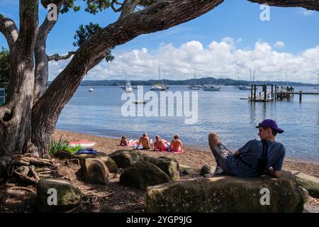 Les gens se relaxent sur la plage surplombant le port et la marina à Russell, Bay of Islands, North Island, Nouvelle-Zélande Banque D'Images