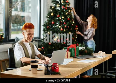 Les jeunes professionnels s'engagent dans la décoration joyeuse de vacances tout en profitant de leur espace de travail de bureau Banque D'Images