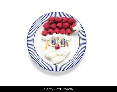 Assiette avec crêpe en forme de Père Noël sur fond blanc. Fête de Noël Banque D'Images